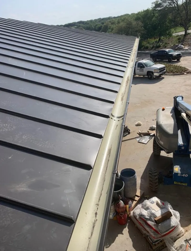 Standing seam panel and gutter detail on a metal roofing jobsite in Manville